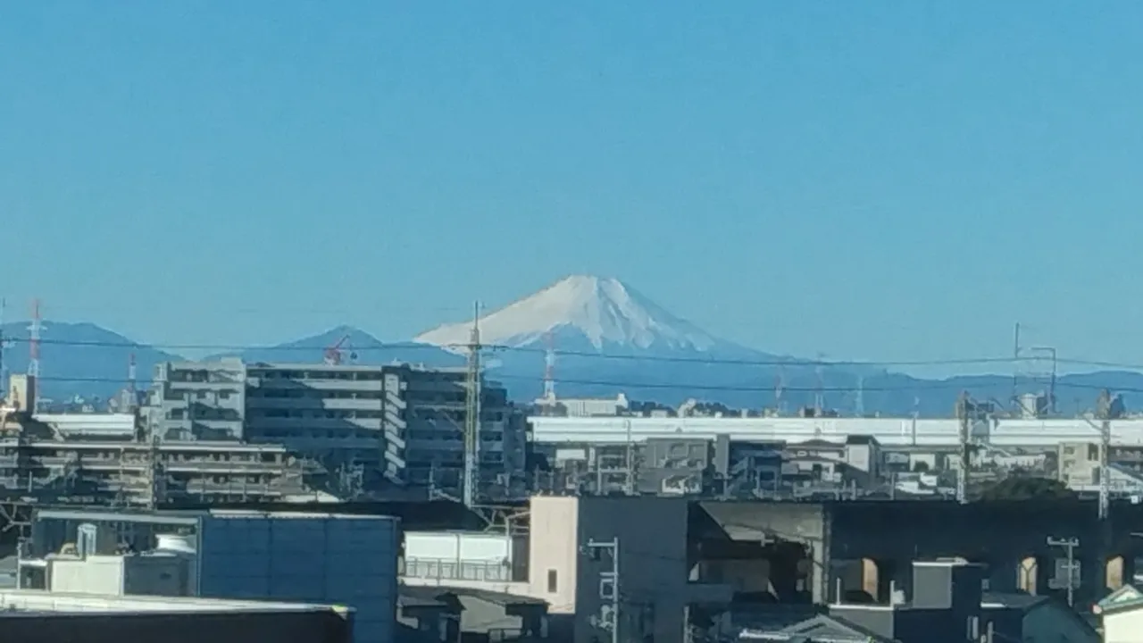 車窓越しに見える雪化粧の富士山と冬晴れの青空